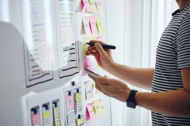 Stock photo of a person writing on a board of sticky notes.