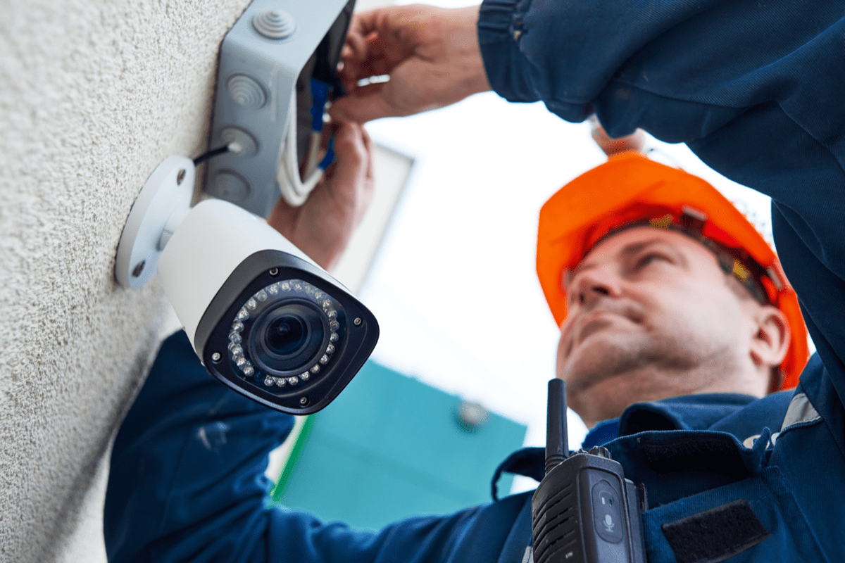 Stock image of an electrical worker fixing a security camera.