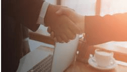 Stock photo of two people in suits shaking hands.